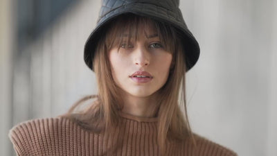 Person wearing a blue bucket hat with a neutral background